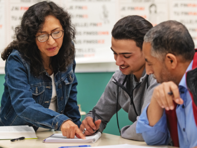 The image shows adult learners in a class.