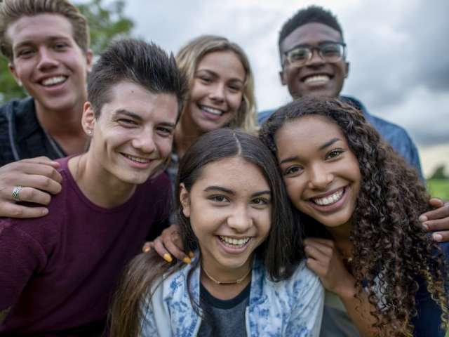 Group of six young people smiling at the camera.