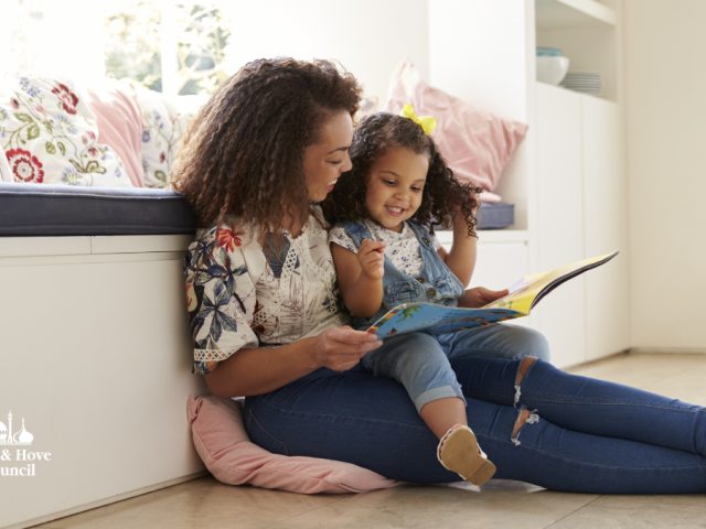 Picture of woman and small child reading while sitting on the floor.