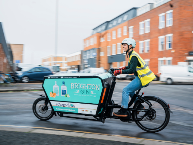 A person riding an ecargo bike, a bike with a large box on the front