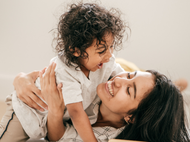 The image shows a parent cuddling her child.