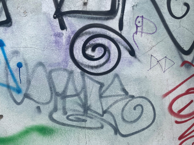 Photo of black, grey, red and purple tags on a white wall.