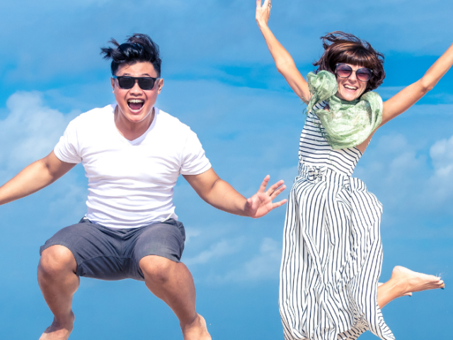 The image shows two young people jumping for joy.