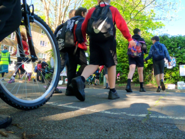 children walking across a road and a bicycle wheel