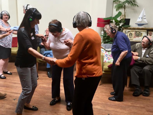 Photo of 7 older people dancing with headphones on