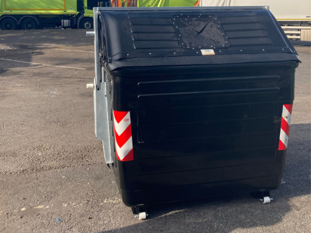Photograph of a large black refuse bin.