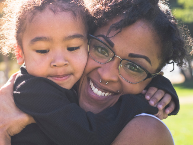 The image shows a mother holding her young child.