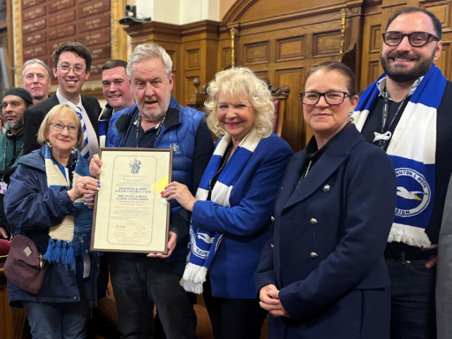 9 councillors in blue and white holding the Freedom of the City certificate