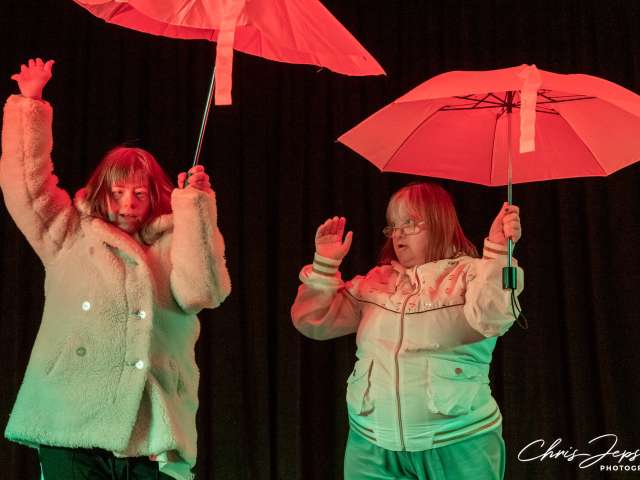 photo of two ladies dancing holding umbrellas