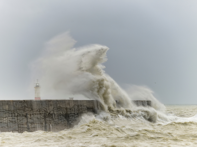Photo of a wave crashing on a wall.