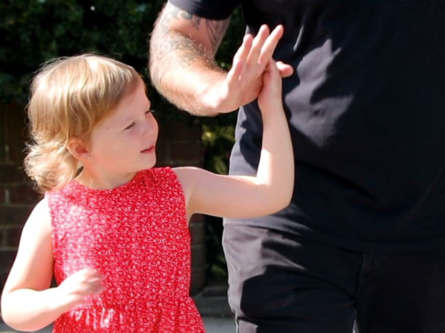 A little girl crossing a road with an adult