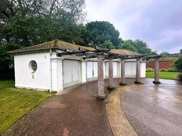 A picture of a white building with paving, grass and trees
