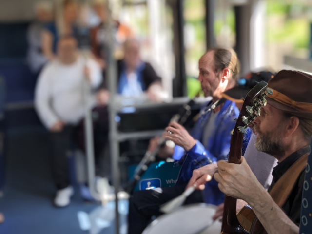Musicians entertaining people on a bus during an event for Dementia Awareness Week