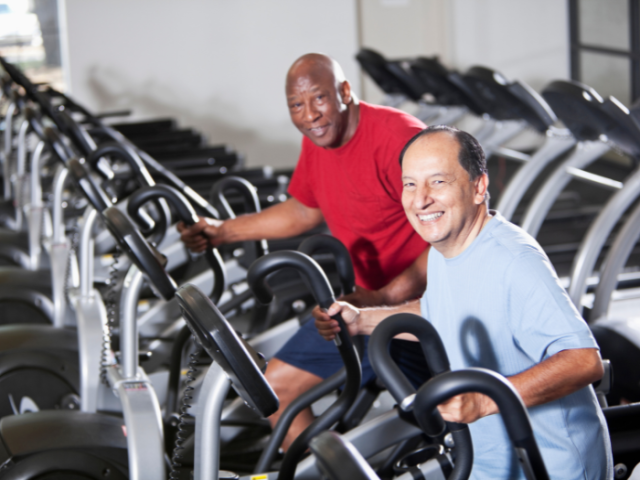 two men using exercise machines in gym