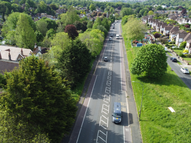 An aerial view of a road with trees and grass either side