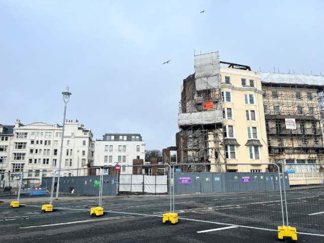 A picture of a derelict building and road with barriers