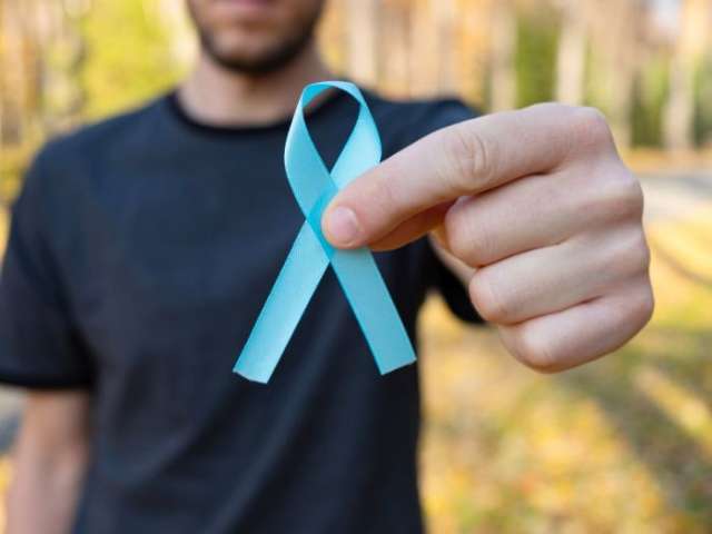 A man holding a blue ribbon, recognised as a symbol for raising awareness of prostate cancer
