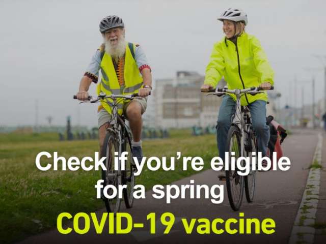 A man and a woman cycling along Hove seafront. Text reads: "Check if you're eligible for a spring Covid-19 vaccine."