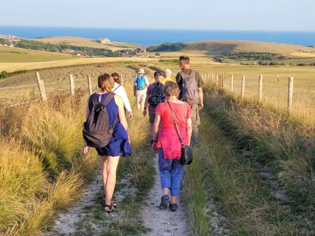 A group of people walking over the hills towards the sea