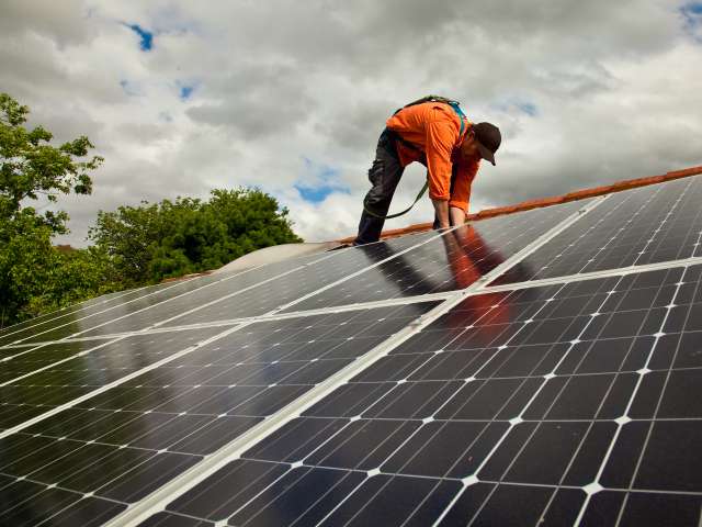 Electrician on roof fitting solar panels