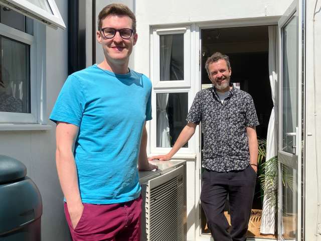 Hove resident Louis and Councillor Tim Rowkins with the heat pump outside the back door of the house.