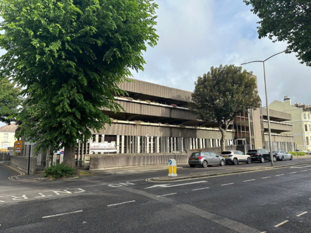 A photo of a car park with trees and cars parked on the street