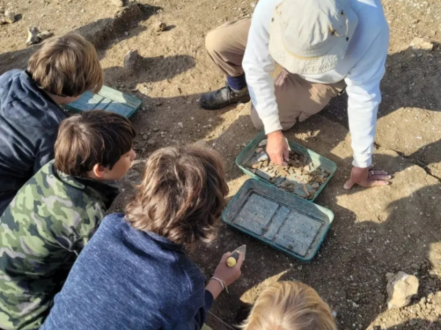 Picture of children helping to sift soil as part of an archaeological dig in Bevedean 