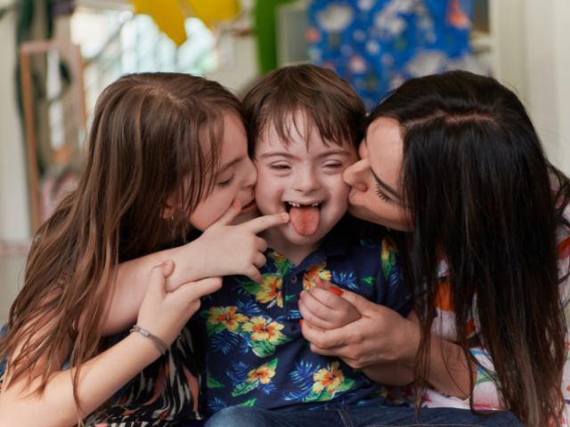 A photo of 2 people kissing a child on the cheeks