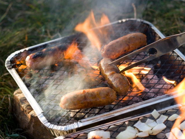 a picture of a disposable BBQ with sausages cooking on it