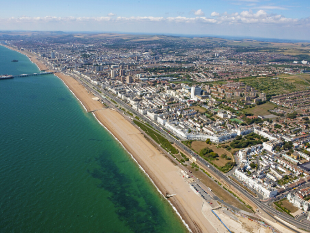 A drone shot of a city with the sea and buildings and roads