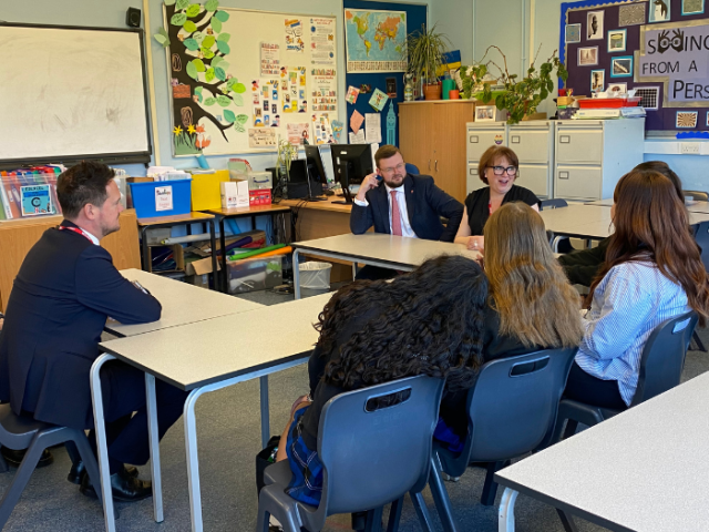The image shows Councillors Jacob Taylor and Emma Daniel, as well as the Minister for Early Education, Stephen Morgan MP speaking to three girl students at Patcham High School.