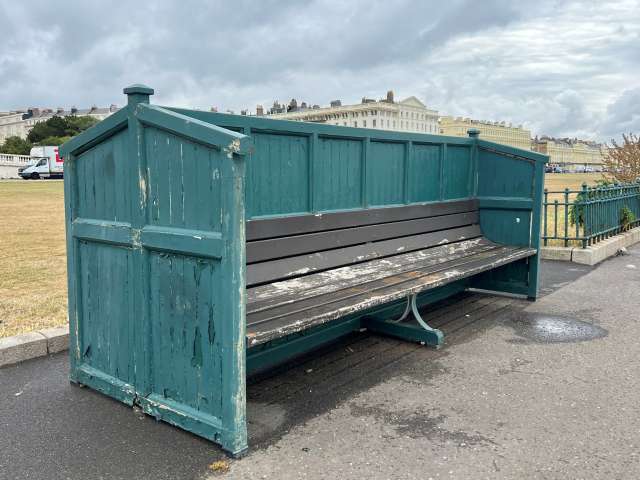A wooden bench, with green frame, in slight disrepair, on Hove seafront.