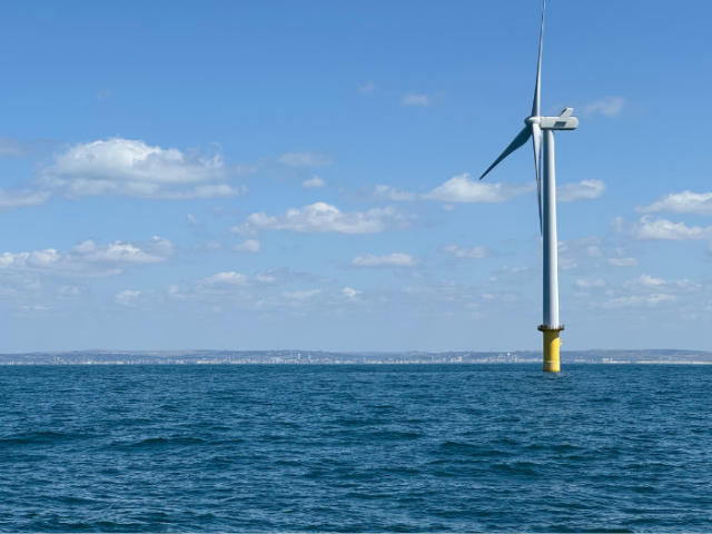 A view of Brighton & Hove from out to sea, with a wind turbine on the right side of the image