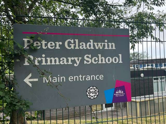 Peter Gladwin Primary School entrance sign with the school building and tree in the background.