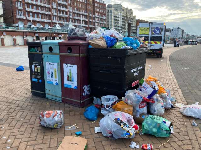 Seafront bins pictured with overflowing bags of rubbish left on top and next to them.
