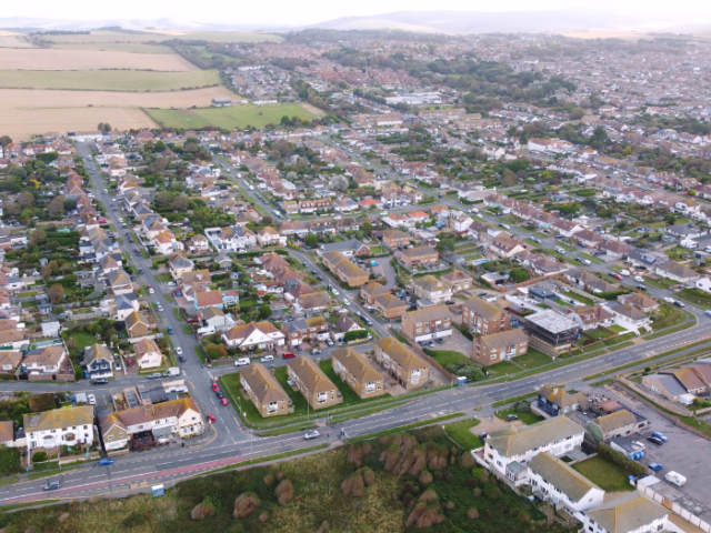 An aerial view of streets with housing and fields at the top