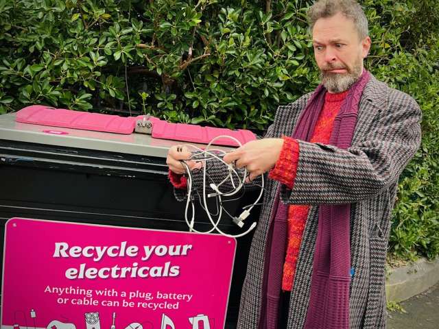 Councillor Tim Rowkins untangling cables ready to recycle in the pink small electricals bin.