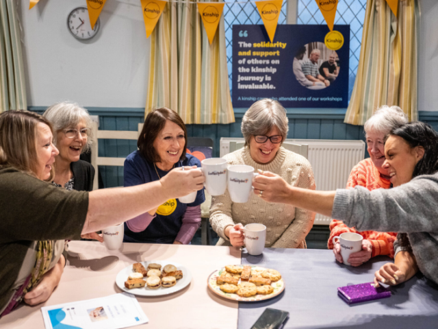 A group of people at a table toasting with cups of tea