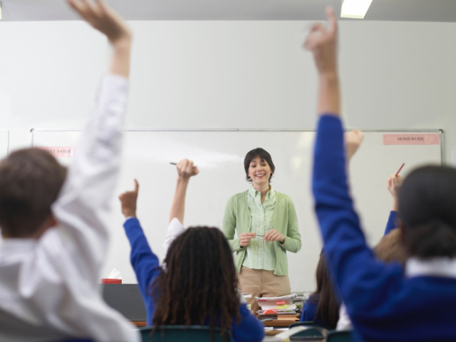A group of students raising their hands in a classroom