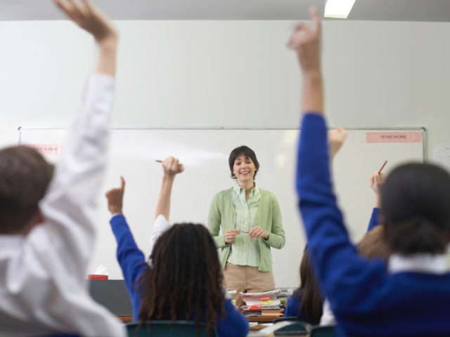 A group of students raising their hands in a classroom
