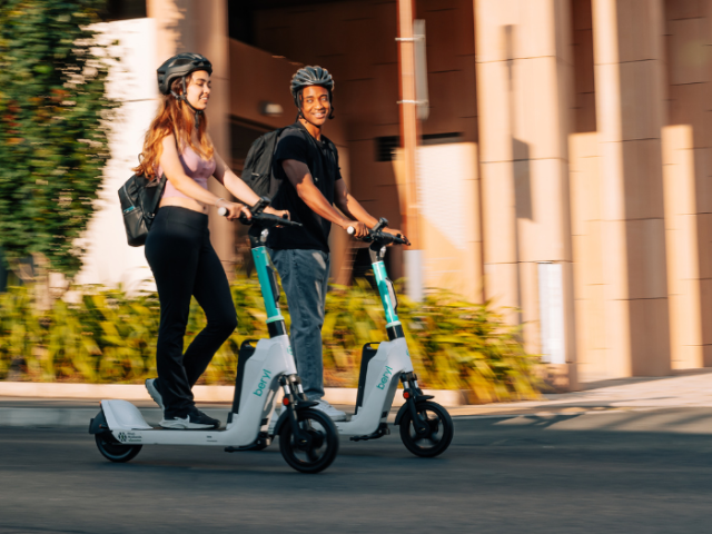 Two people riding e-scooters