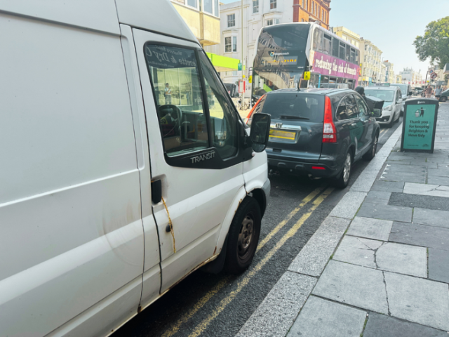 A picture of cars parked on a road with double yellow lines