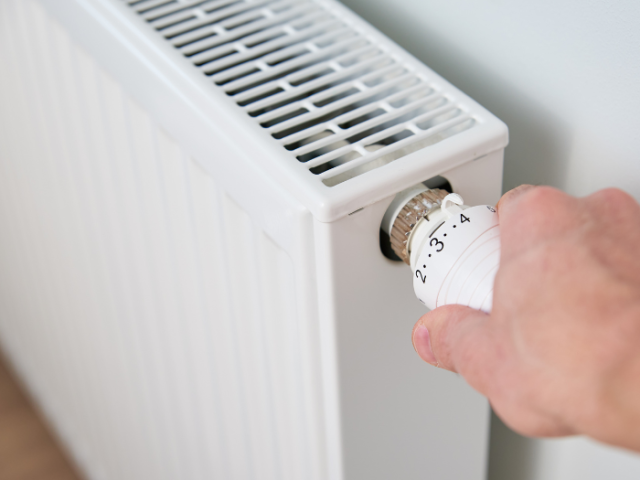 An image of a man's hand turning up the radiator.