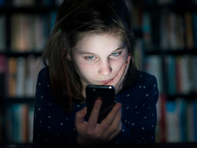 The image shows a girl looking at a smartphone, looking stressed.