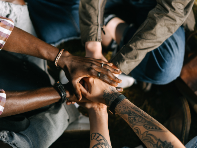 Group of people with interlocking hands showing support