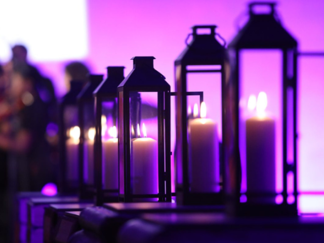 A photo of multiple lit lanterns on a purple background.
