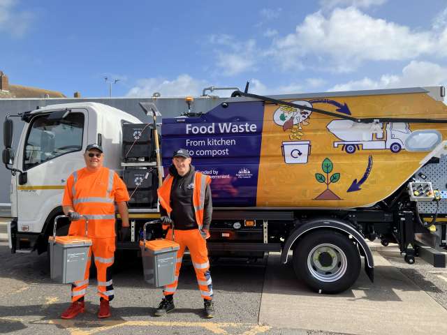 Food waste collection truck ready to go out with 2 crew members carrying caddies