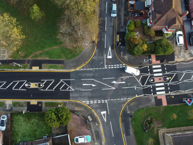 a drone shot of a road junction with traffic islands, a zebra crossing and a white van