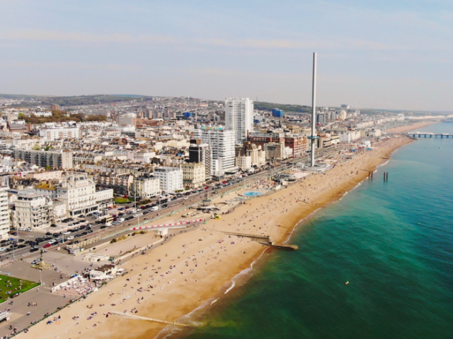 A drone shot of a seafront with a city in the background