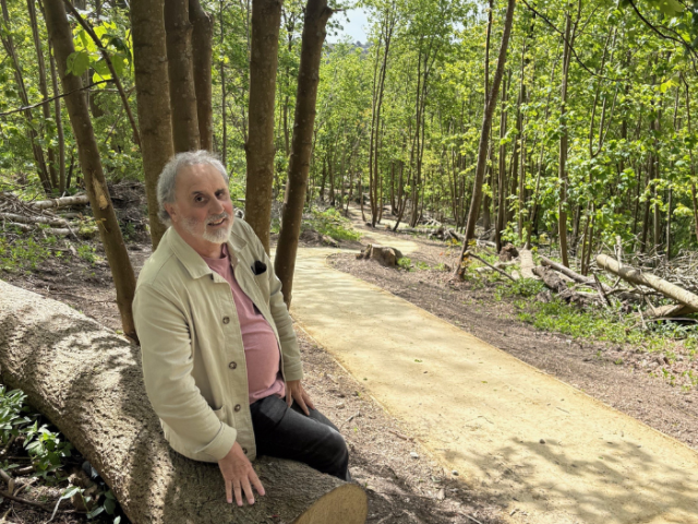 Councillor Alan Robins takes a rest on a fallen log beside the renovated footpath at Coldean
